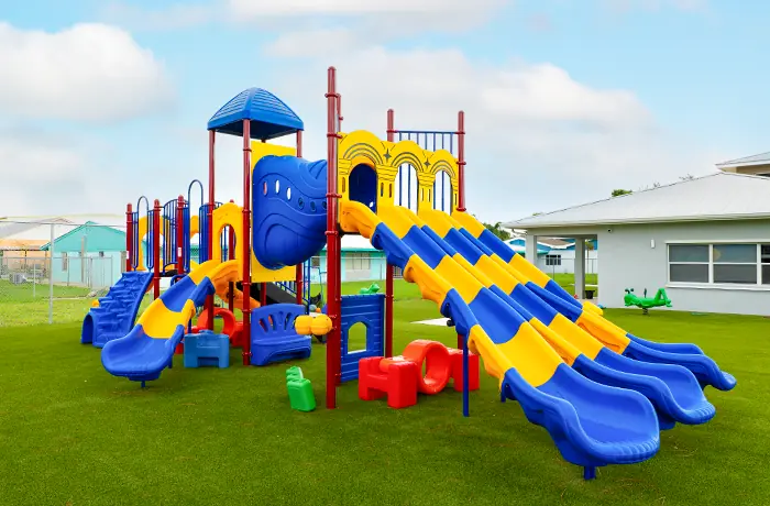 Completed playground by Pro Playgrounds with blue and yellow multi-lane slides on turf