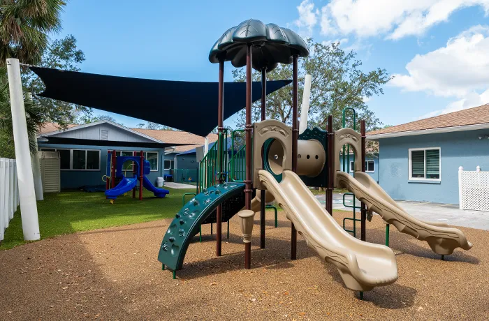 Completed playground by Pro Playgrounds with slides and shade sail over rubber surface