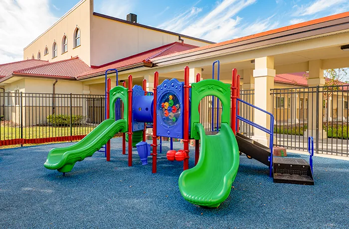 Daycare playground with slides and activity panels on rubber surface, installed by Pro Playgrounds