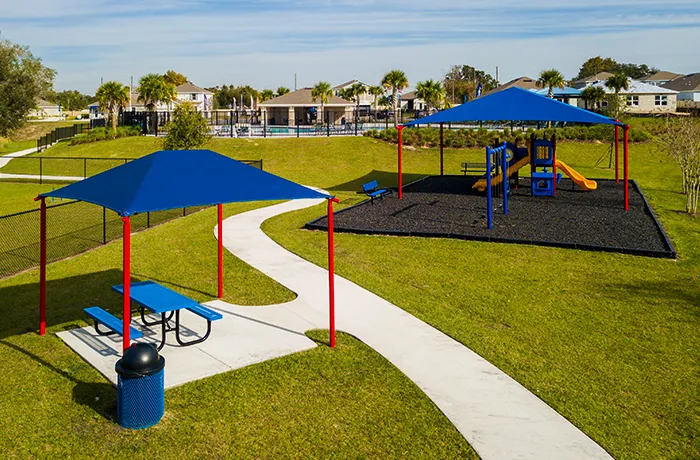 Park playground with shade structures, picnic table and play area, installed by Pro Playgrounds