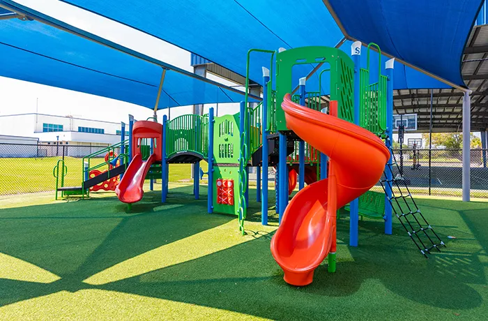 Play structure with slides on synthetic turf, completed playground surfacing installation by Pro Playgrounds