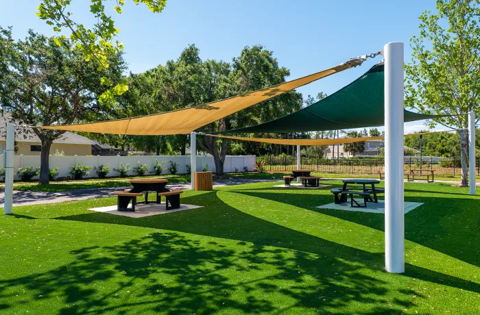 Completed shade structure installation by Pro Playgrounds with tan and green sail shades over picnic area