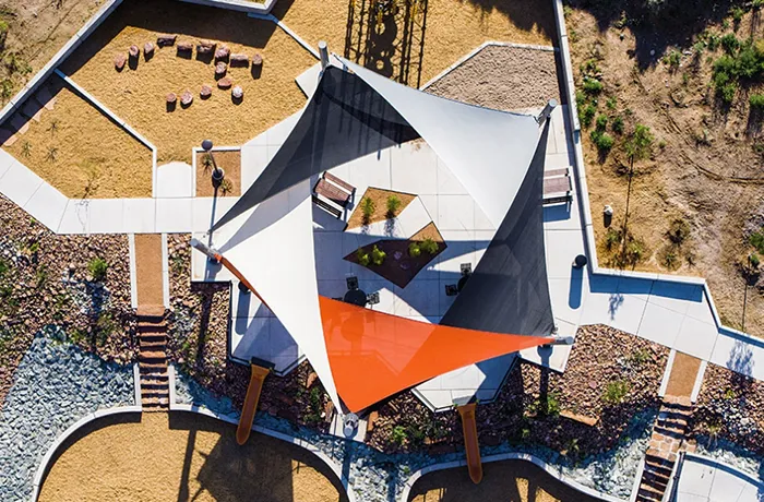 Aerial view of navy and orange triangular shade sails over landscaped plaza seating area