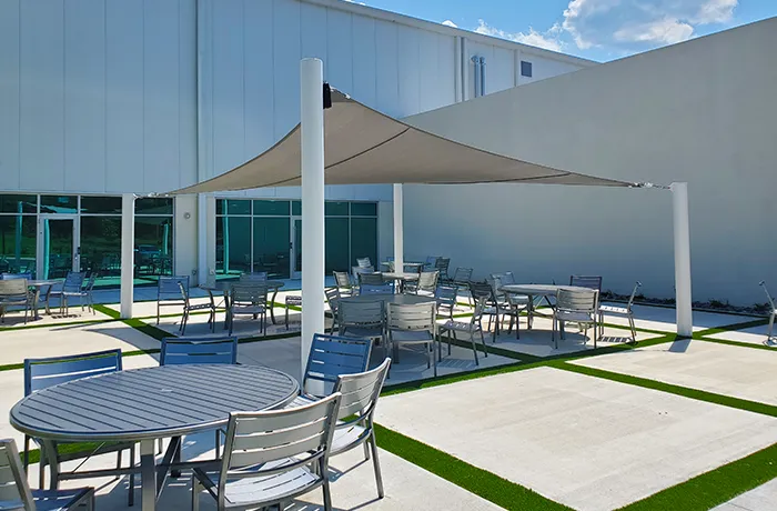 Completed shade structure installation by Pro Playgrounds with square shade sail over outdoor patio seating area.
