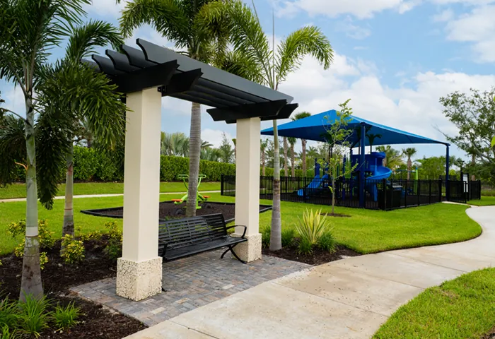 Commercial metal bench under pergola near playground, installed by Pro Playgrounds