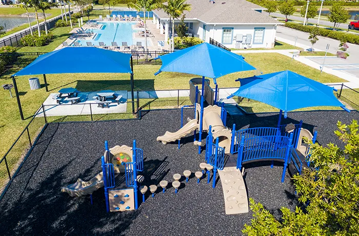 Blue play structure with shade canopies and picnic tables, completed playground by Pro Playgrounds
