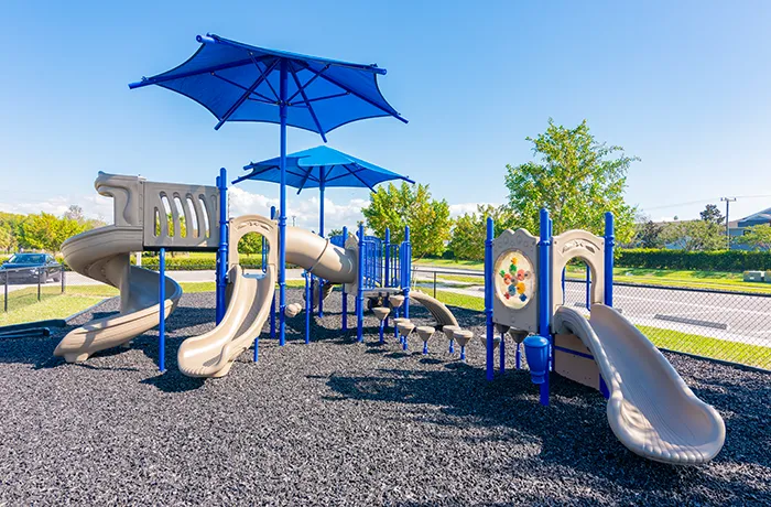 Completed playground by Pro Playgrounds with blue and beige play structures and multiple slides.