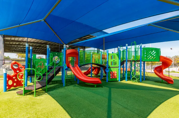 Completed municipal playground by Pro Playgrounds with shaded play structures, slides, and climbing features.