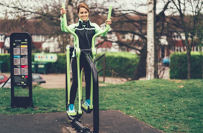 Woman using outdoor fitness machine in community park