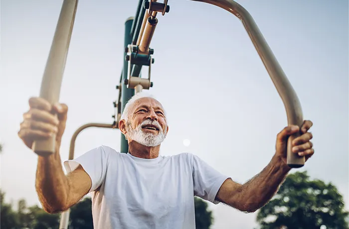 Older man using outdoor chest press fitness machine in park
